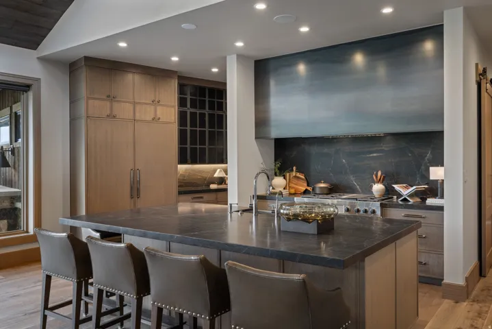 Kitchen island with dark countertop, integrated sink, and stainless steel faucet
