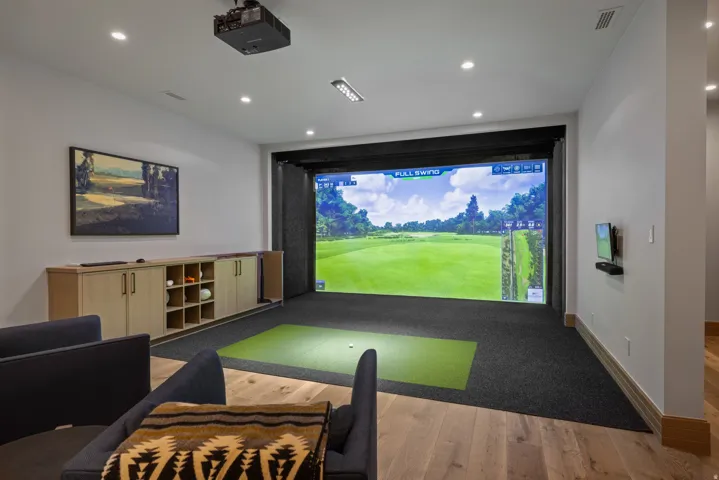 Dedicated golf simulator with an impact screen, integrated projector, and recessed lighting
