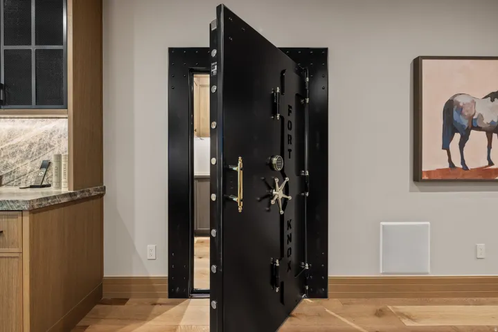 Custom vault door with gold-finish hardware, wood-finish flooring, and light-toned walls