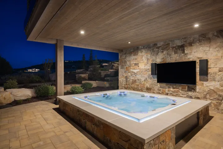 Built-in spa with integrated lighting, stone surround, and flush-mounted television