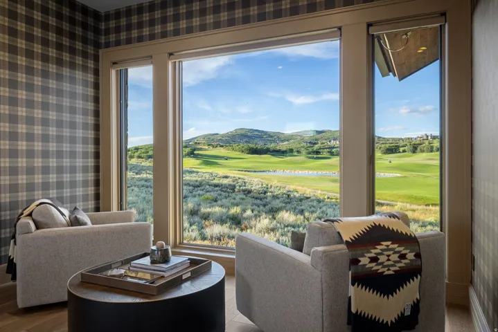 Floor-to-ceiling windows, plaid wall covering, and wood-finish flooring