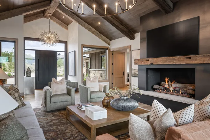 Vaulted wood-beamed ceiling with exposed trusses, stone-clad fireplace with a reclaimed wood mantel, and a built-in media center