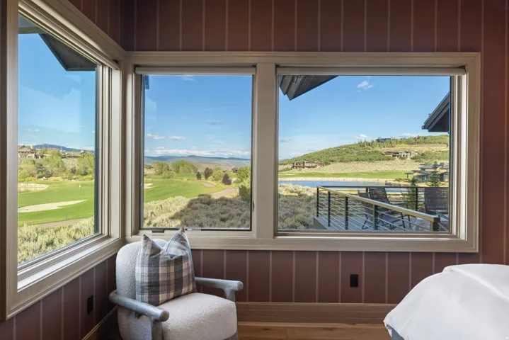 Expansive windows with a golf course backdrop, a lake, and distant mountains