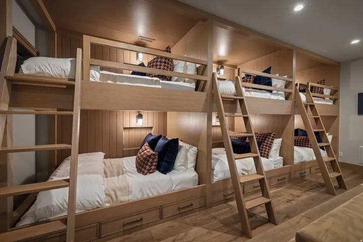 Custom built-in bunk beds with wood-finish paneling, individual sconce lighting, and integrated storage drawers