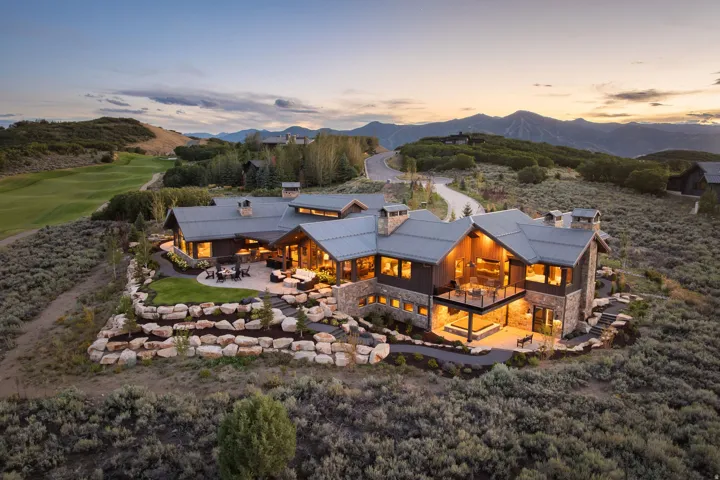 Stone and wood-clad exterior with multiple balconies, a patio, and tiered landscaping