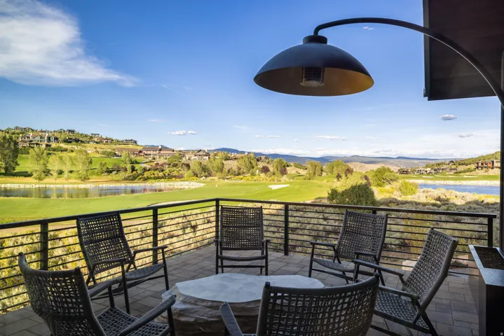 Spacious outdoor patio with stone paver flooring, horizontal bar railing, and a large overhead heat lamp