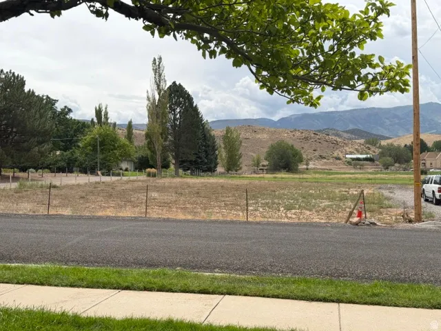 Expansive land parcel featuring natural ground cover, framed by distant mountains and scattered mature trees
