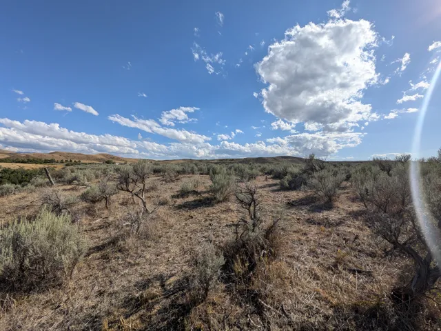 Expansive undeveloped land featuring natural shrubbery and distant hills