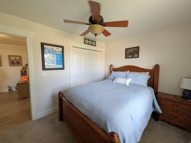 Ceiling fan, wood-finish bed frame, carpeted flooring, wood-finish flooring, paneled bifold closet doors