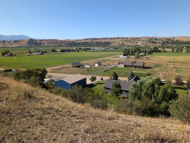 Expansive landscape featuring distant mountains, agricultural fields, and multiple residential structures