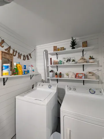 Laundry area with white shiplap walls and multiple wall-mounted shelving units