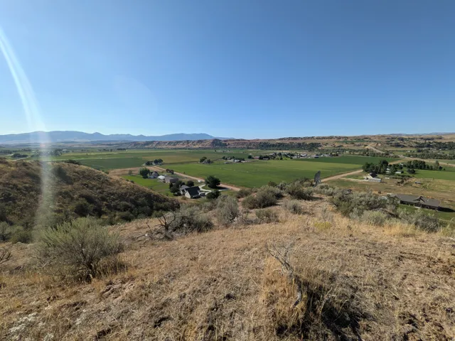 Valley views from the acreage on property. Rolling hills with varied terrain, distant mountains, and expansive green agricultural fields