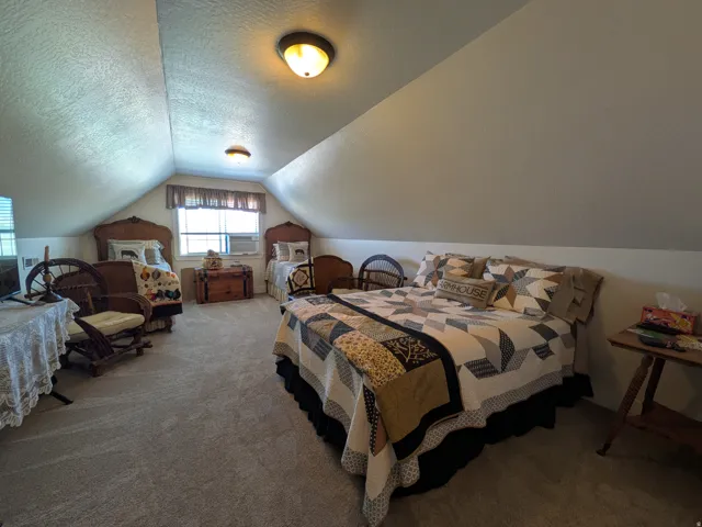 Carpeted room featuring sloped ceilings, multiple windows, and flush-mount lighting fixtures