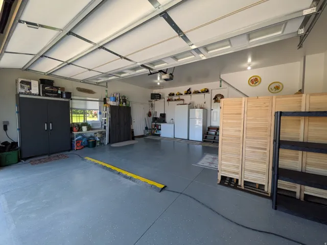 Spacious garage with an overhead door, finished flooring, and multiple ceiling-mounted light fixtures