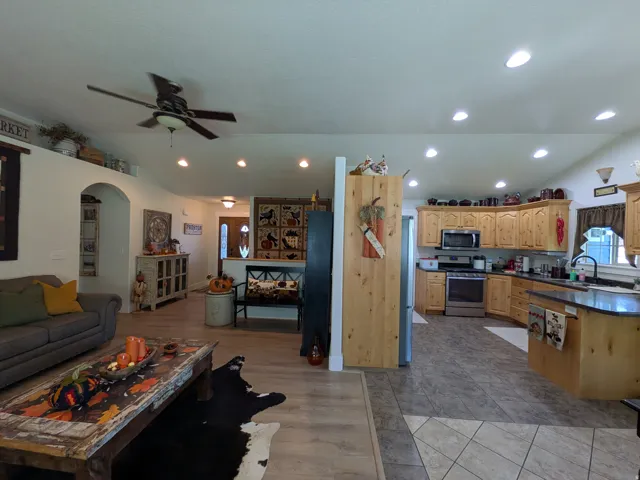 Recessed lighting, wood-finish flooring, arched doorway, wood cabinetry, and stainless steel appliances