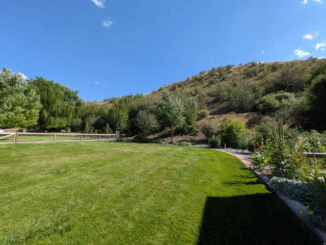 Expansive lawn bordered by mature trees and a terraced garden bed