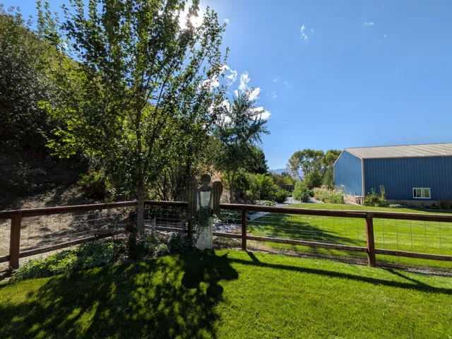 Expansive green lawn with mature trees and wood-post fencing