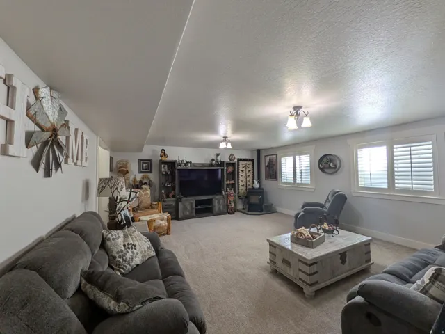 Carpeted living area featuring multiple windows with plantation shutters, recessed lighting, and a built-in media console
