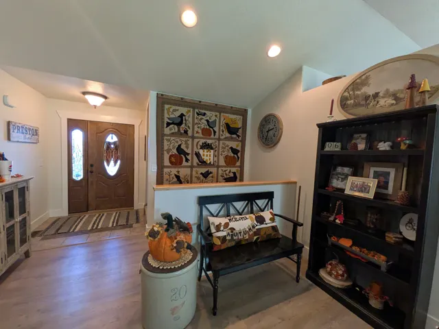 Wood-finish flooring throughout, solid wood entry door with decorative glass, and recessed ceiling lighting