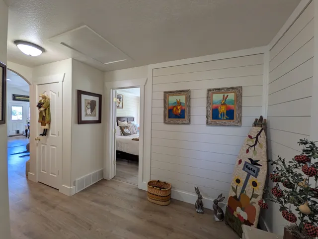 Bright hallway featuring shiplap wall paneling, wood-finish flooring throughout, recessed ceiling lighting, and multiple doorway access points