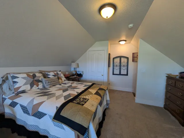 Carpeted flooring, vaulted ceiling, and flush-mount lighting