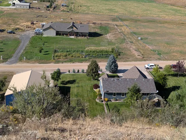 Expansive property featuring two distinct residences, a large metal-sided outbuilding, established landscaping, and a fenced garden area