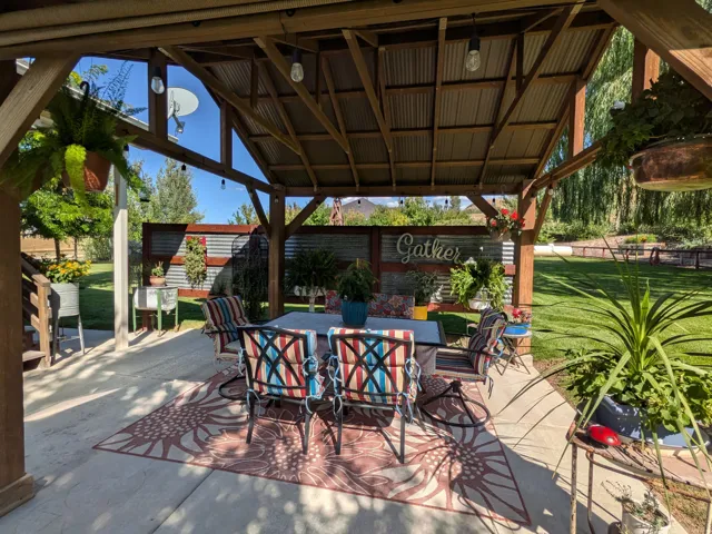Expansive concrete patio featuring a wood-frame pergola with a corrugated metal roof