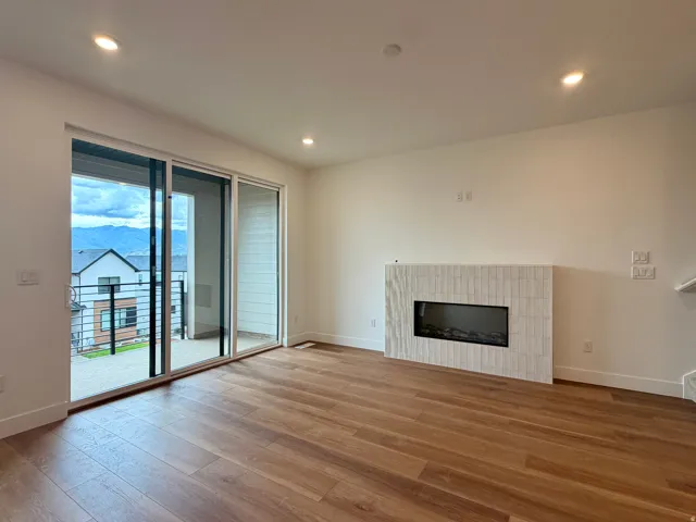 Spacious room featuring wood-finish flooring, a built-in electric fireplace with a tiled surround, and recessed ceiling lighting