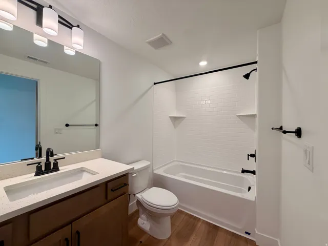 Bathroom featuring a single vanity with stone-look countertop, wood-finish cabinetry, and matte black fixtures