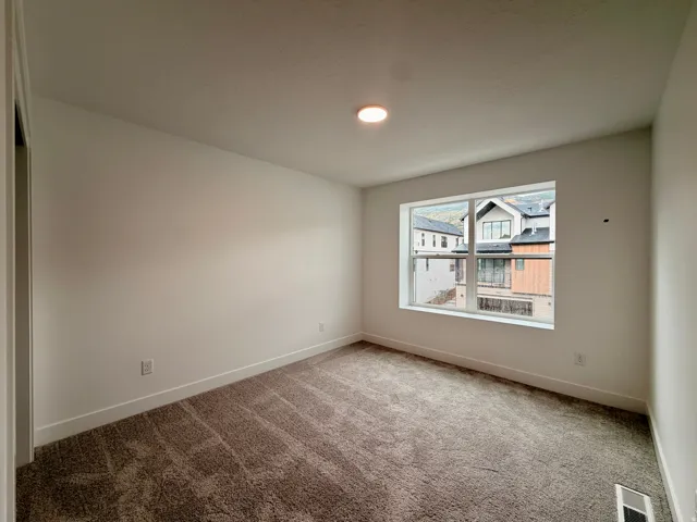Secondary bedroom with recessed lighting, neutral carpet flooring, white walls, and a large window with white trim