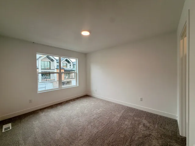 Secondary bedroom with recessed lighting, neutral carpet flooring, white walls, and a large window with white trim