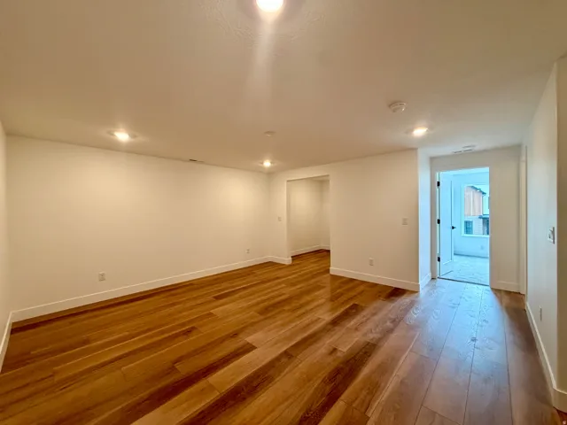 Wood-finish flooring throughout, complemented by recessed ceiling lighting and white painted walls