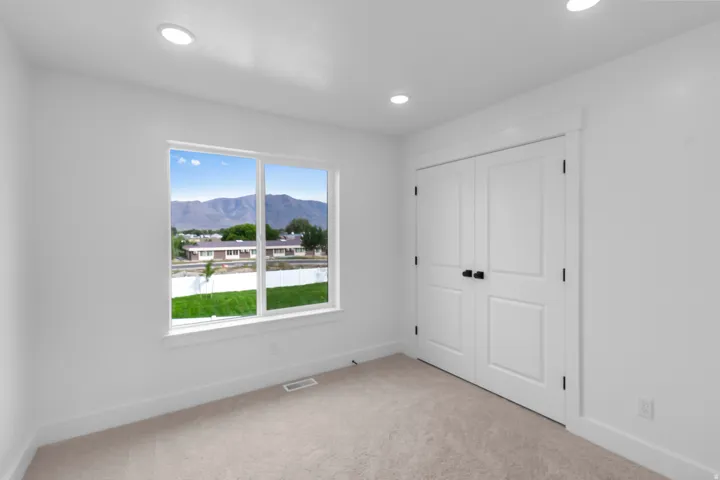 Recessed lighting, neutral carpeting, white interior walls, white paneled double doors with matte black hardware, and a large window with white trim