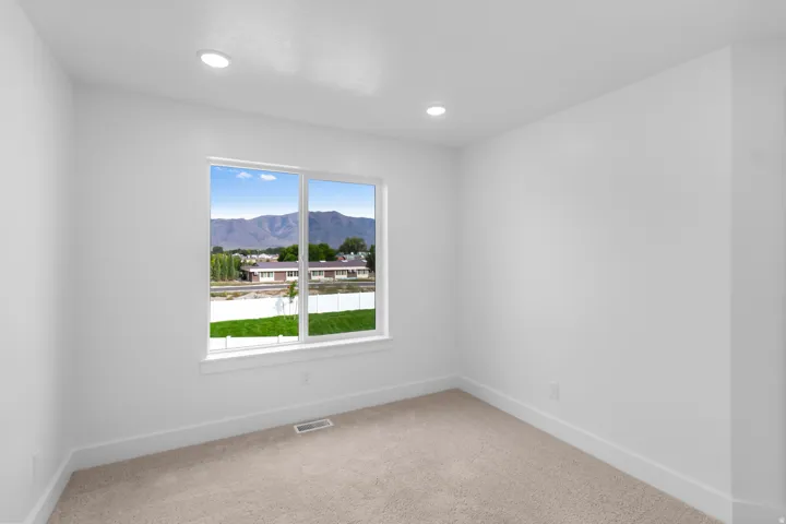 Neutral wall color, recessed ceiling lighting, a large window, and carpeting