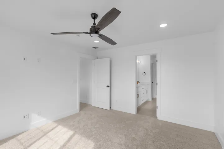 Plush carpeting, recessed lighting, and a modern ceiling fan with wood-finish blades