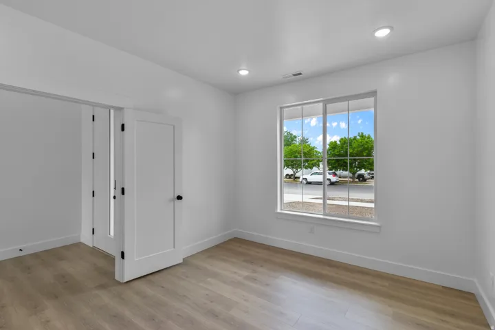 Recessed lighting illuminates this room featuring wood-finish flooring, white walls, and a large window