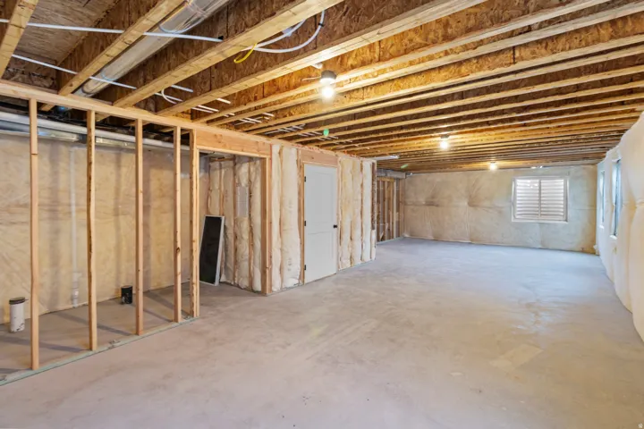 Partially framed lower level with exposed ceiling joists, concrete flooring, and insulated exterior walls