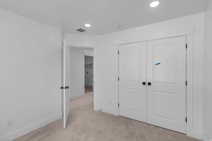 Neutral tone wall paint, recessed lighting, double panel doors with matte black hardware, and plush carpet flooring