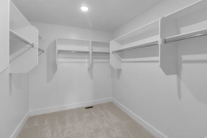 Walk-in closet featuring built-in shelving, chrome hanging rods, recessed ceiling lighting, and carpet flooring