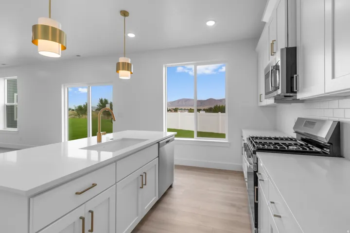 Kitchen featuring a large island with an integrated sink, gold-tone hardware, a stainless steel gas range, and white subway tile backsplash