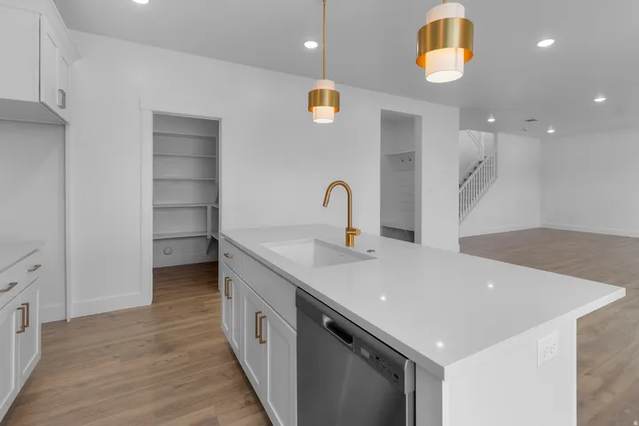 Kitchen island with white countertop, integrated sink, and gold-finish faucet