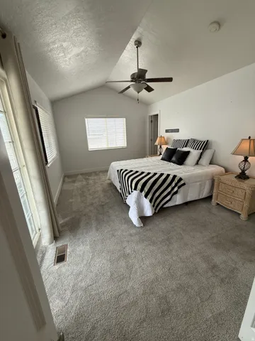 Vaulted ceiling with ceiling fan, wall-to-wall carpeting, and window blinds, Walk in closet, and private balcony