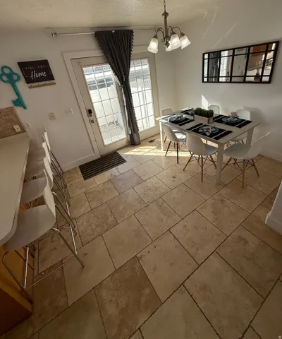 Tile flooring throughout, glass-panel exterior door, and a multi-light chandelier