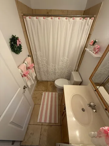 Full bathroom featuring a single vanity with an integrated sink, a toilet, a shower/tub combination with tile surround, and tile flooring