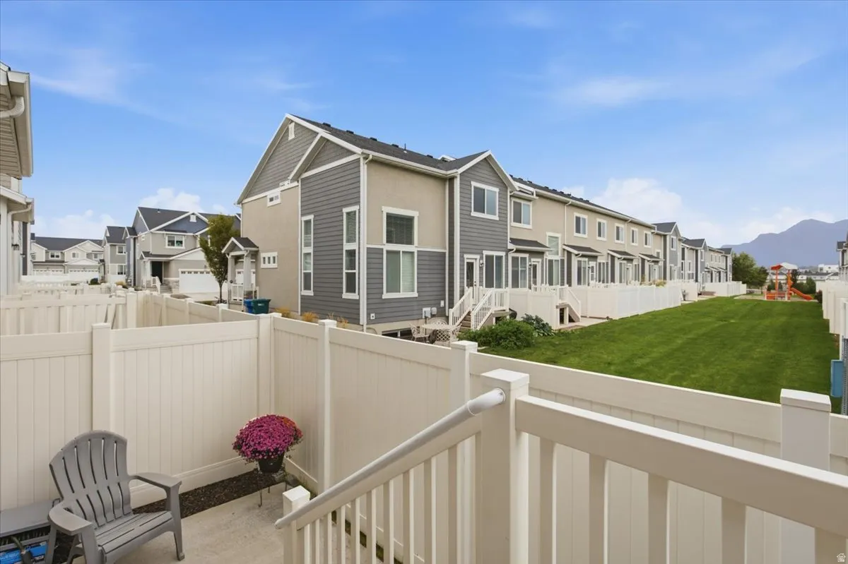 Private patio with a white vinyl fence, offering access to a shared green space