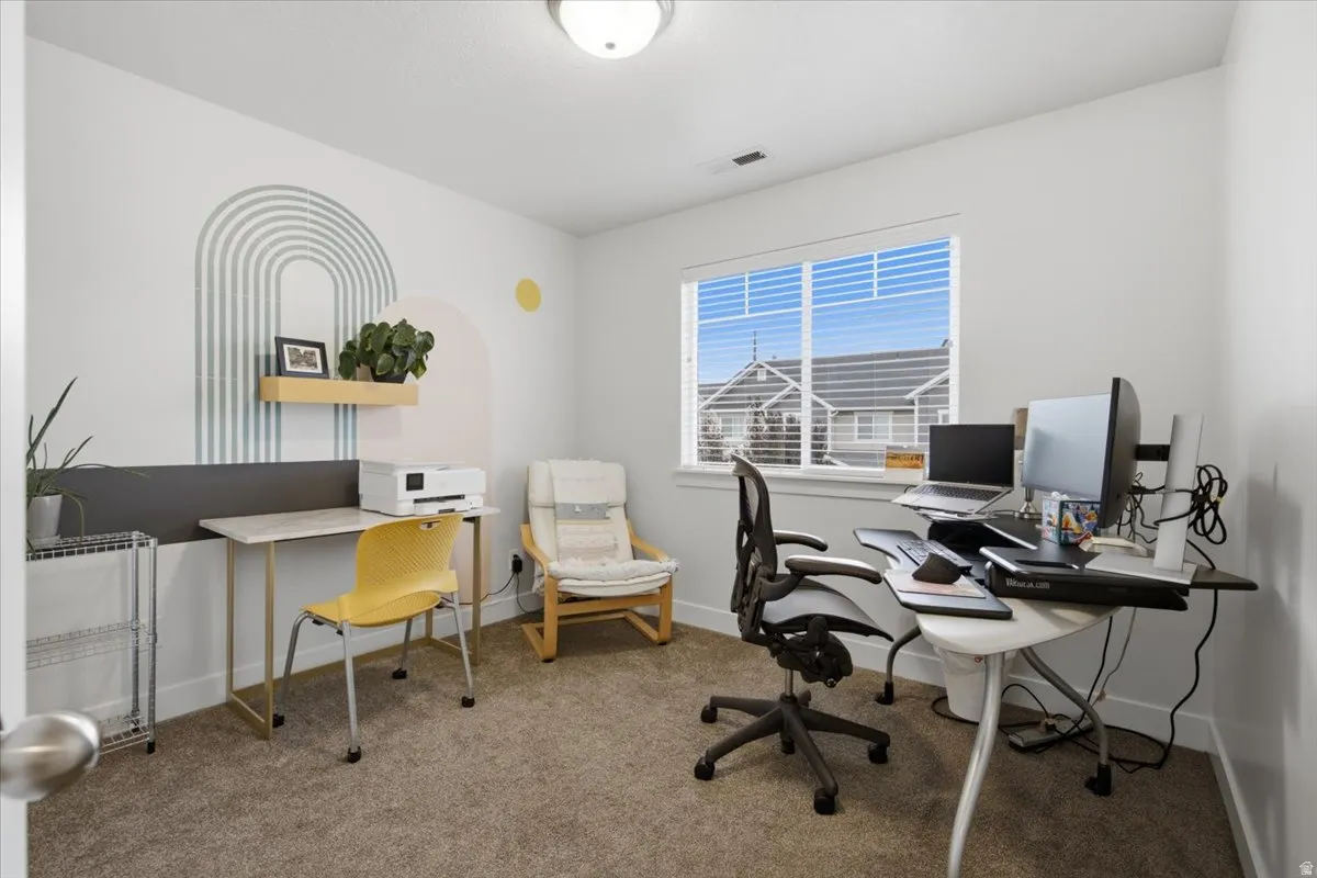 Carpeted room featuring a single window with blinds, a wall-mounted light fixture, and a built-in shelf