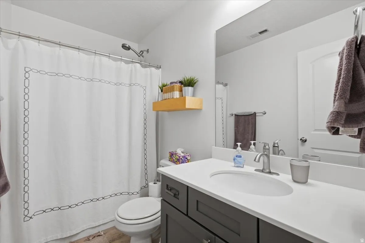 Bathroom featuring a full vanity with an integrated sink, brushed nickel faucet, large mirror, and a shower with a chrome showerhead