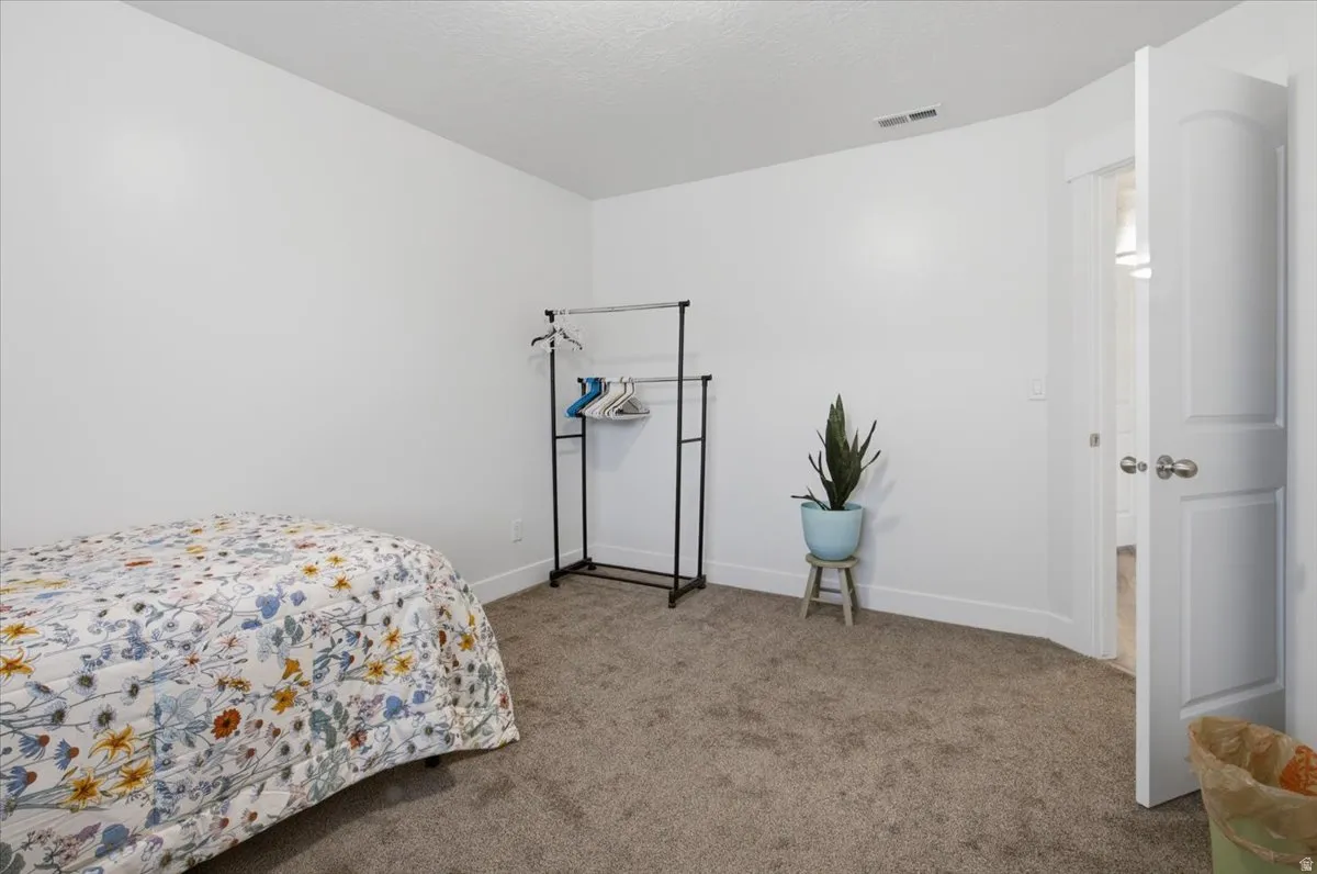 Neutral wall paint, carpet flooring, and a white paneled door with brushed nickel hardware