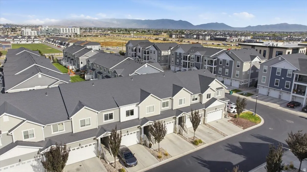 Contemporary townhomes featuring light-toned siding, attached garages, and a paved street
