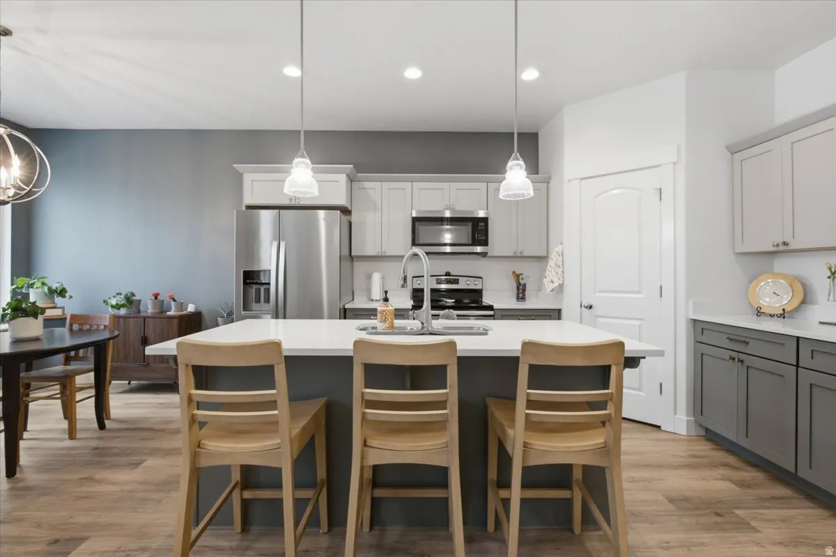 Kitchen featuring an island with white countertop, stainless steel appliances, wood-finish flooring, and recessed lighting